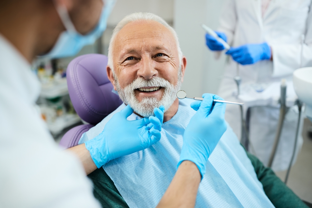 An older man with a beard sits in a dental chair