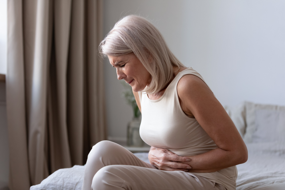 A woman clutching her stomach and wincing in pain