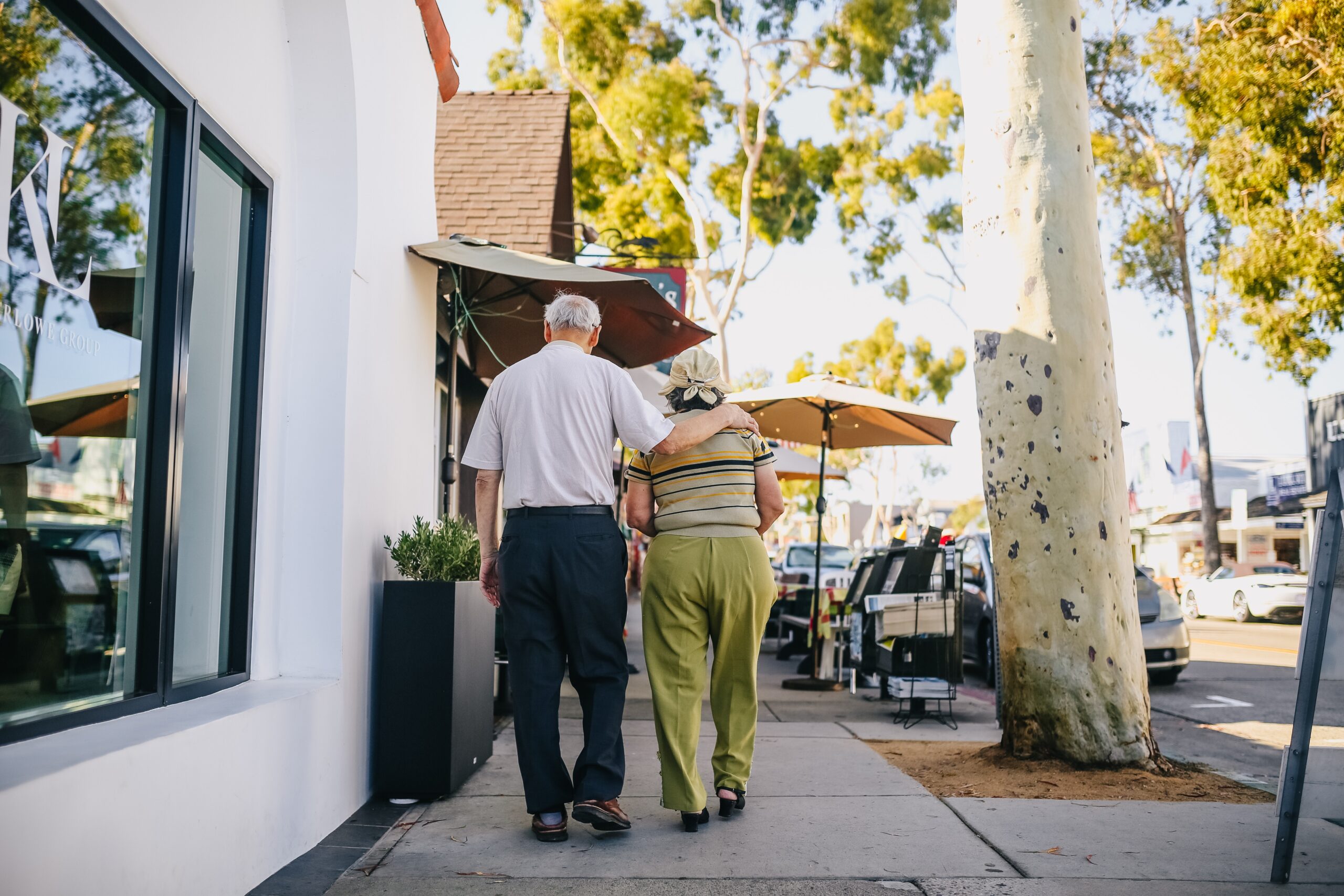 An elderly couple walks arm-in-arm along