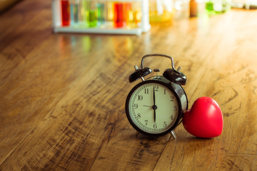 An analog alarm clock and a red heart-shaped object