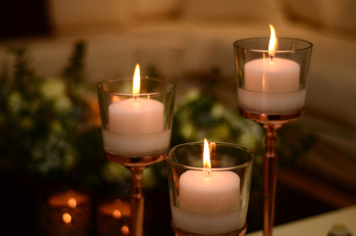 Three lit candles in glass holders on metallic stands