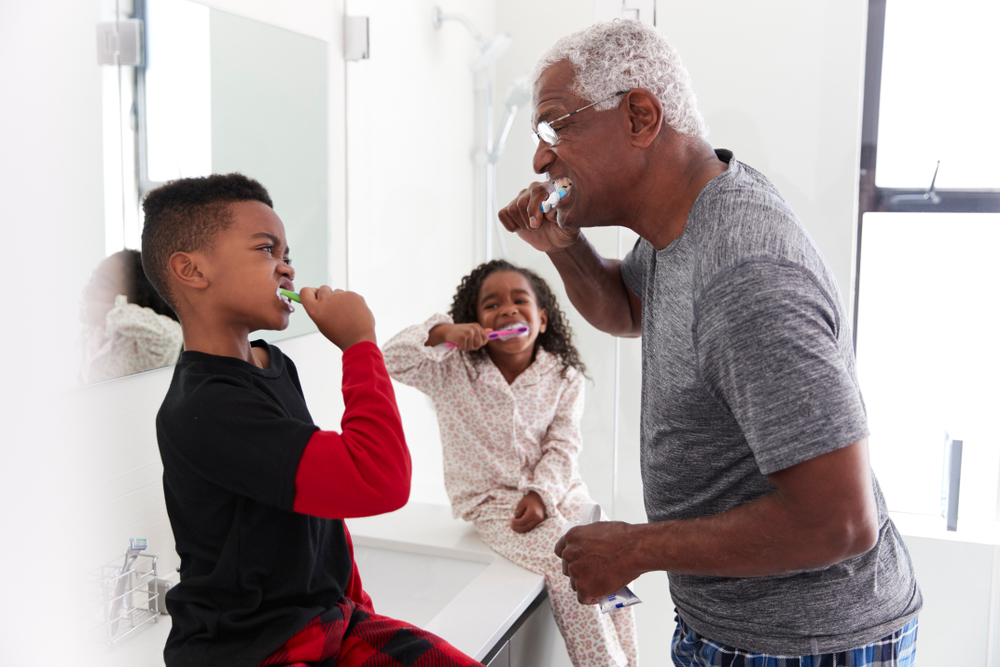 An older man and two children are engaging in personal care