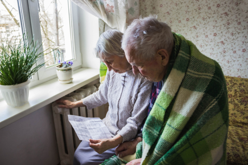 Two elderly people sit by a window, reviewing a document together