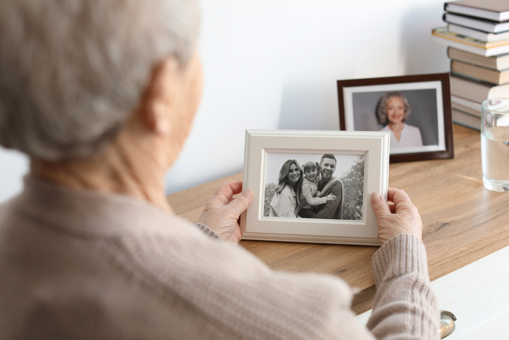 An elderly person holding a framed black-and-white photo