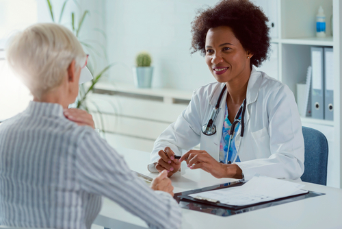 A doctor with an older patient seated across from her at a desk