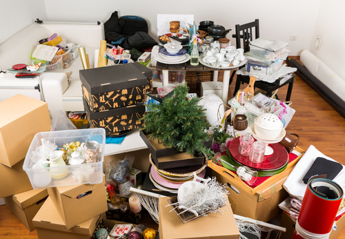 A cluttered room filled with packed boxes, household items, and miscellaneous belongings