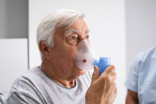 Elderly man using a nebulizer mask for respiratory treatment