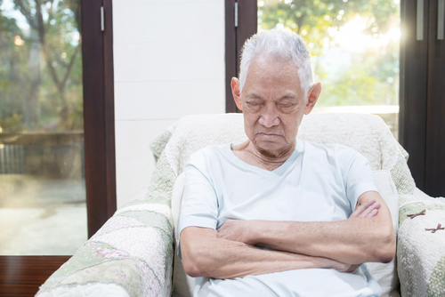 An elderly man asleep with his arms crossed