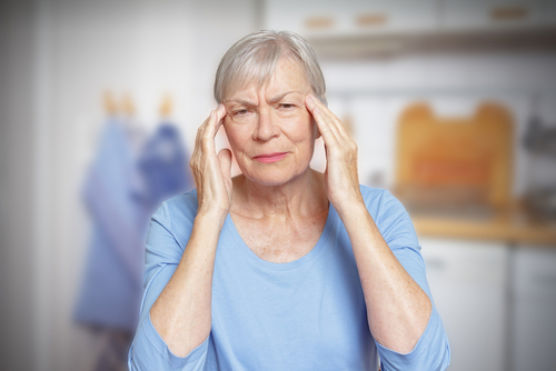 An elderly woman holds her temples