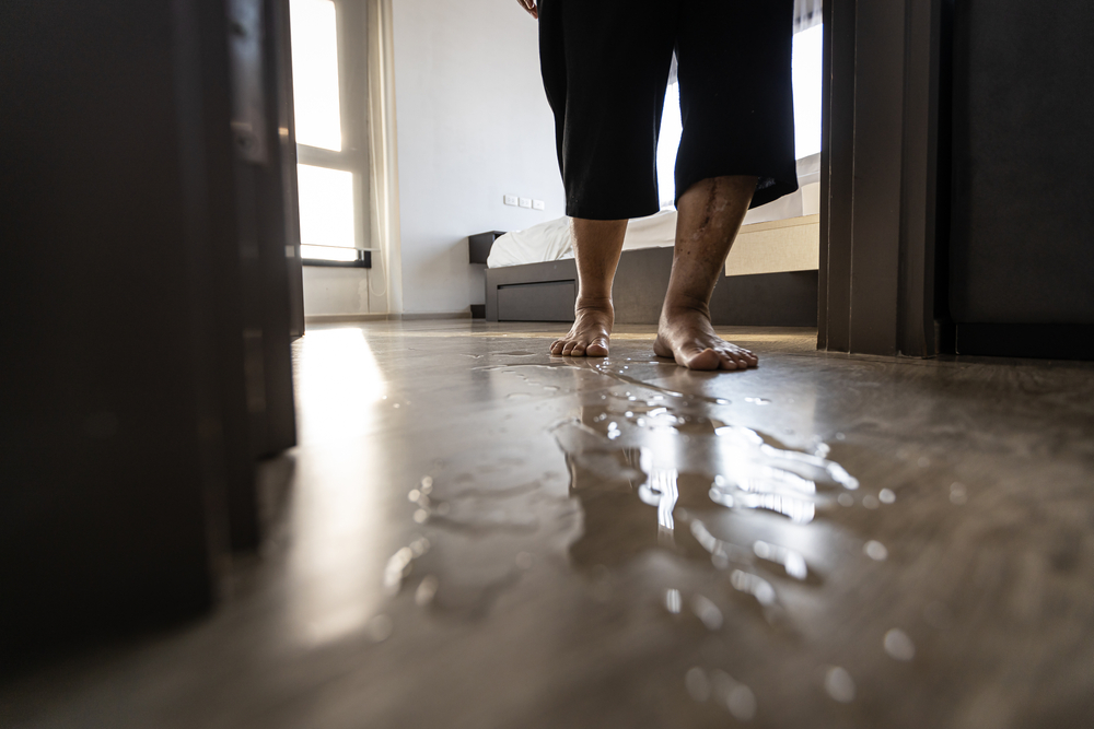 Bare feet of a person stand in a puddle of water