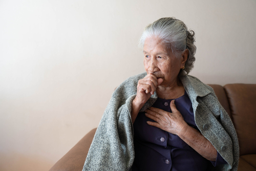 Elderly woman sitting on a couch, wearing a gray shawl