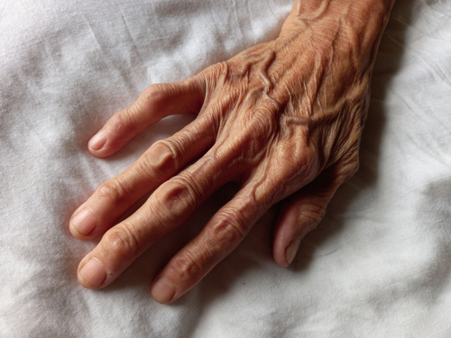 A close-up of an elderly person's hand with visible wrinkles and veins