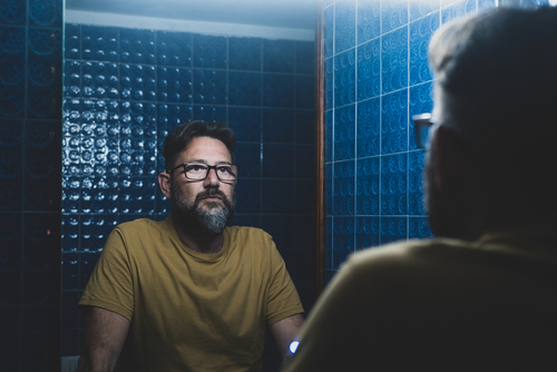 A man reflecting in the bathroom mirror