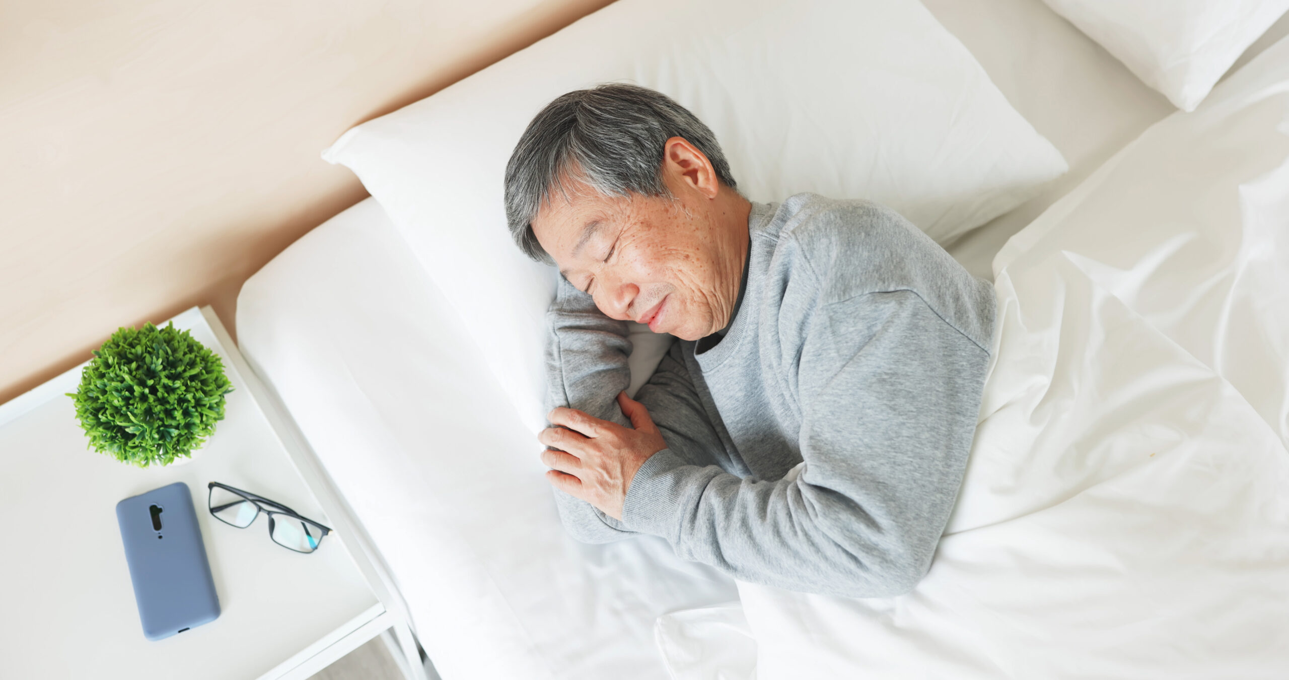 An elderly person is asleep in bed