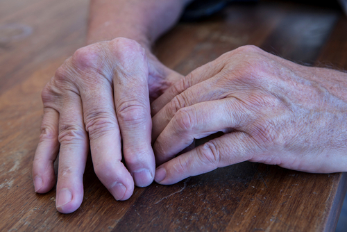 Close-up of two hands resting on a wooden table