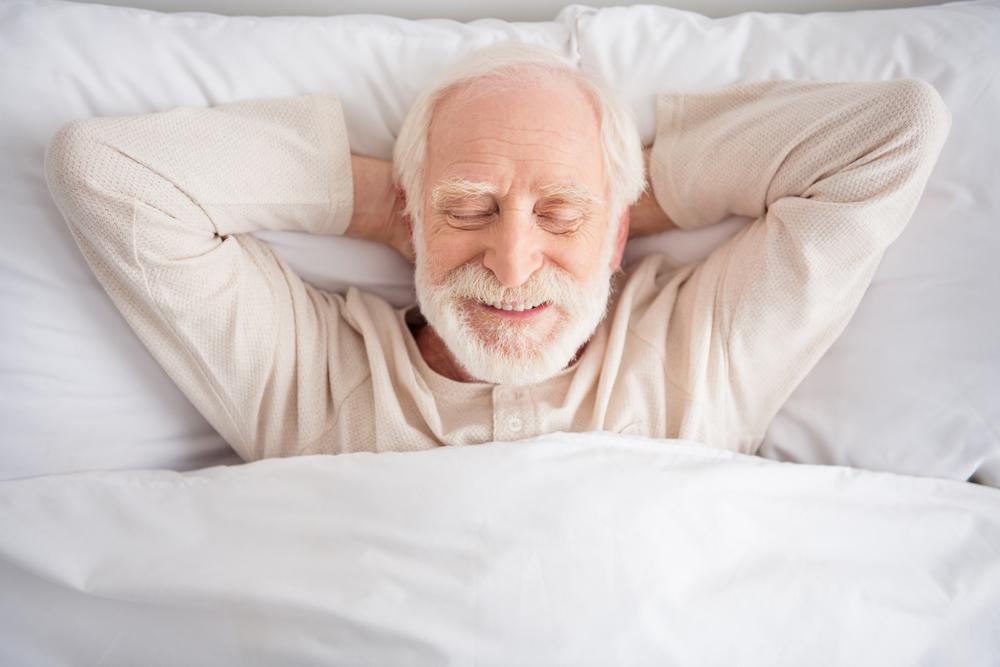 Elderly man smiling while lying in bed