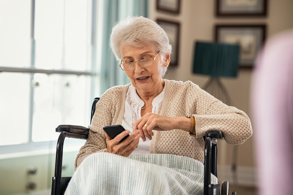 An elderly woman in a wheelchair using a smartphone