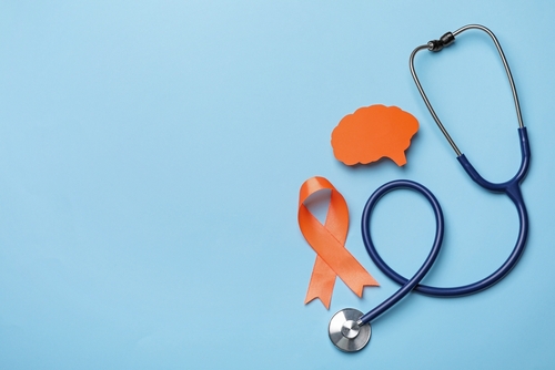 Stethoscope, orange ribbon, and cutout of a brain on a blue background