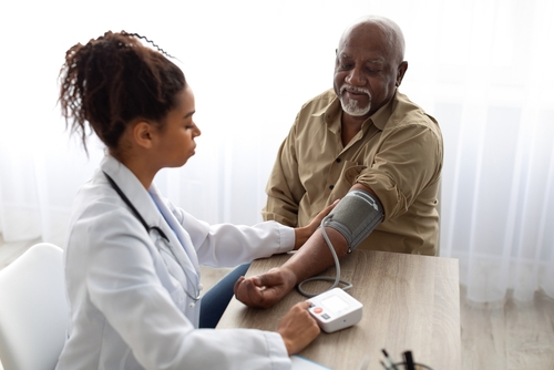 A healthcare professional measures the blood pressure of an elderly man