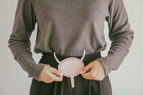 A person holding a paper cutout of a bladder against their abdomen