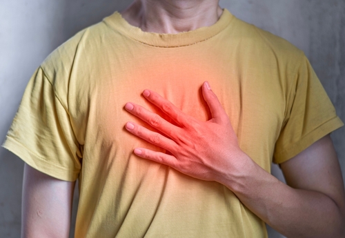 Person in a yellow shirt placing their hand on their chest, with a red glow indicating discomfort.