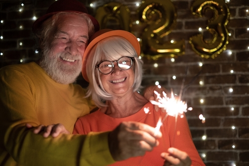 An elderly couple holds a sparkler together