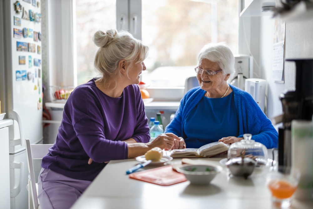 Two older women sit at a kitchen counter