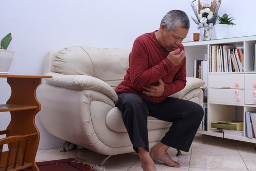 A man in a red shirt and black pants is sitting on a couch