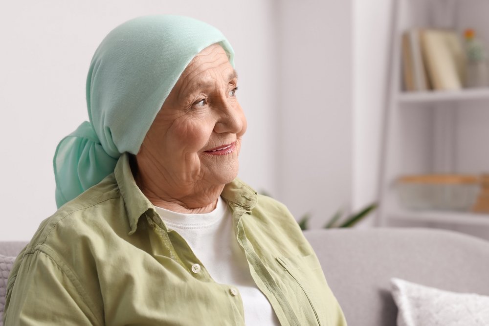 Elderly woman wearing a light green headscarf and a green shirt