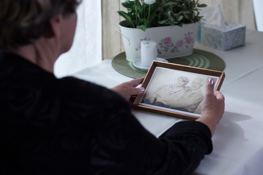 A person is holding a framed photograph of an elderly couple