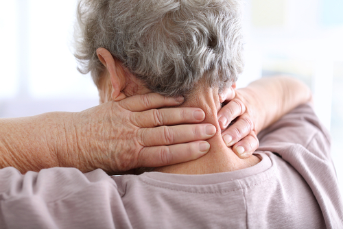 Elderly person, seen from the back, holding their neck with both hands