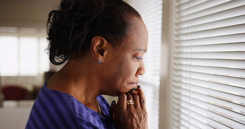 A person looks pensively out a window