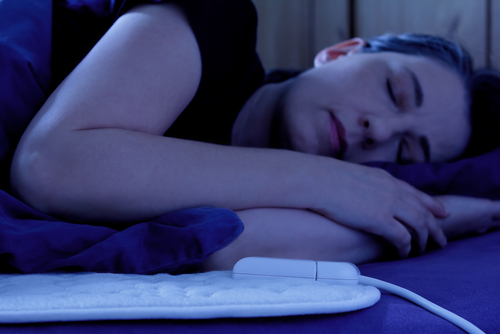 Person sleeping peacefully in a dark room with their head on a pillow