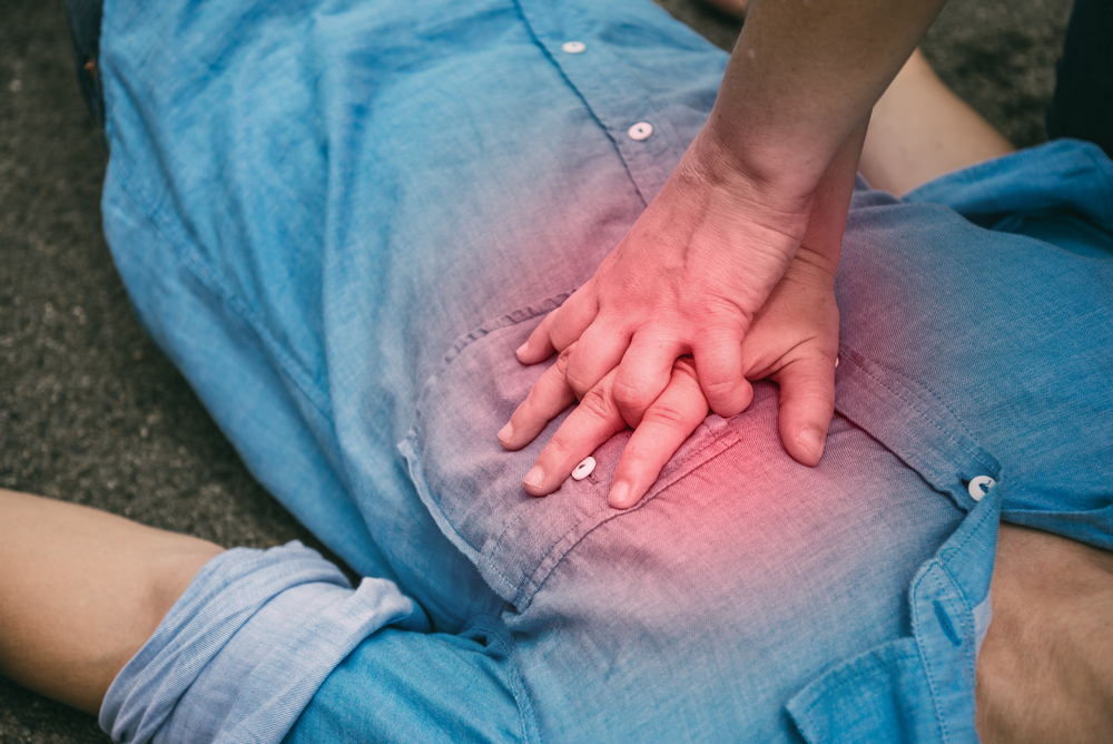 A caregiver performs CPR chest compressions on a person lying on the ground