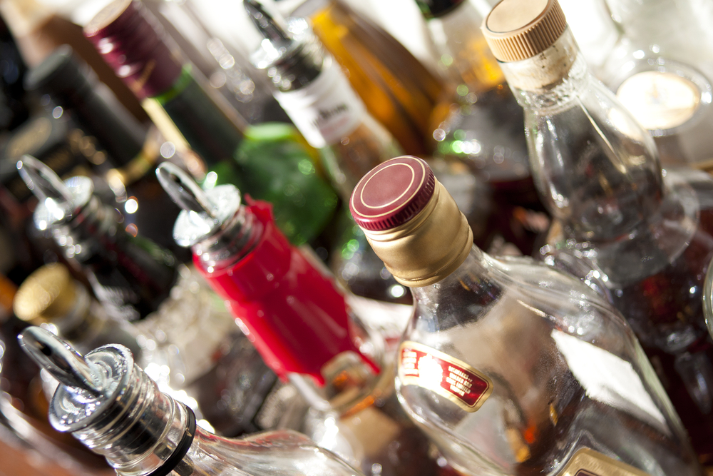 A close-up of various liquor bottles with different colored caps and labels