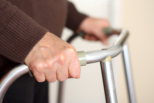 Close-up of elderly hands gripping a walker, providing support and stability