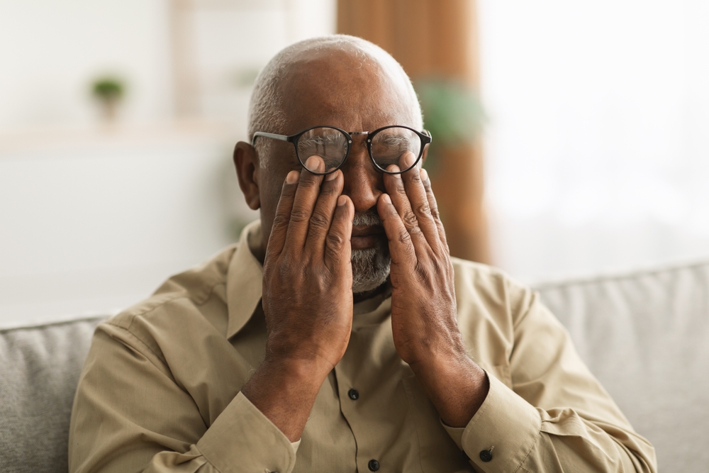 An elderly man rubbing his eyes