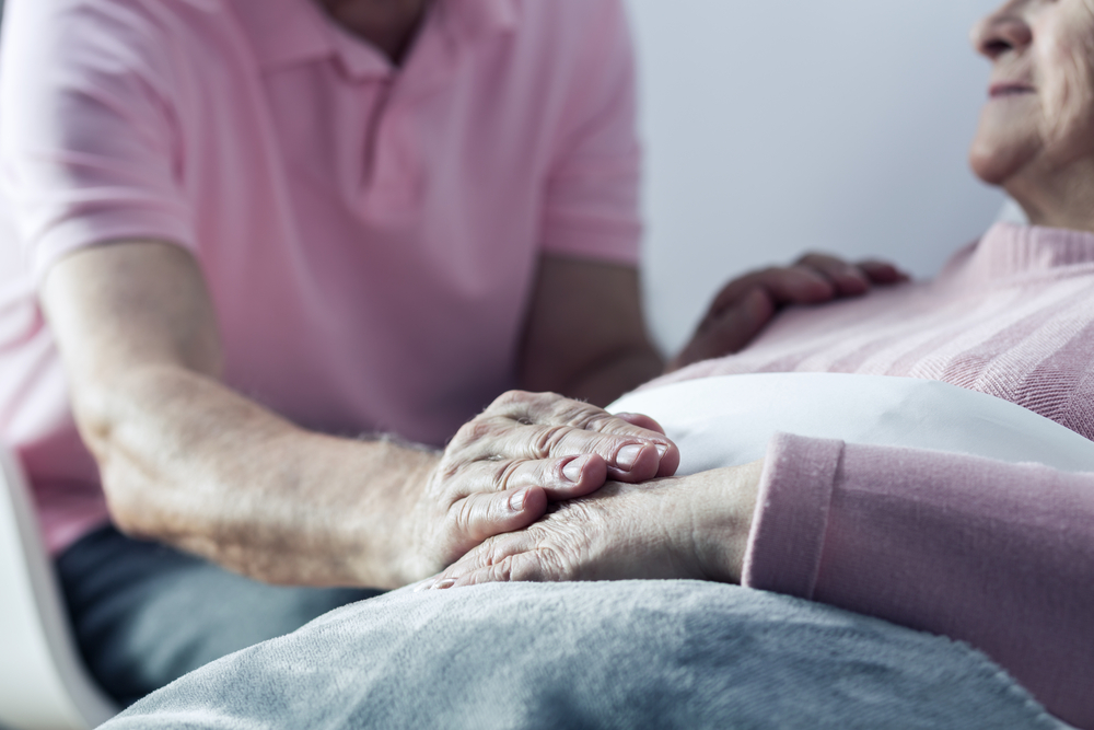 An elderly person lies in bed