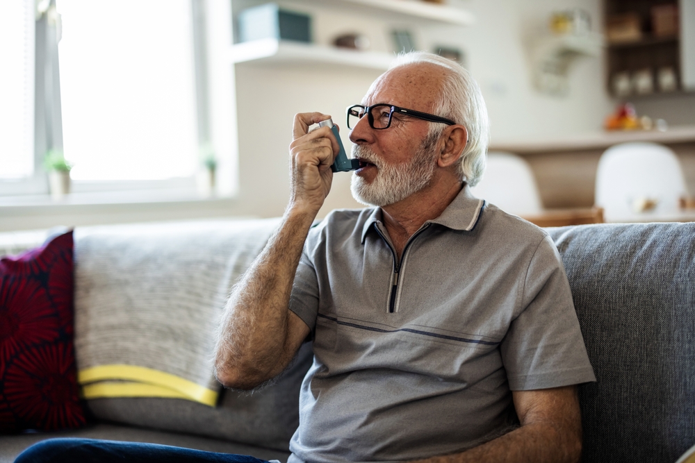 An elderly man using an inhaler