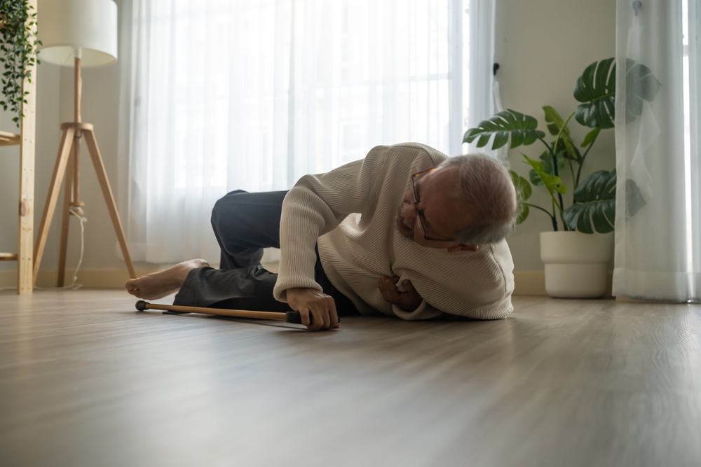 An elderly man lies on the floor next to a cane, highlighting the crucial need for personal care services.