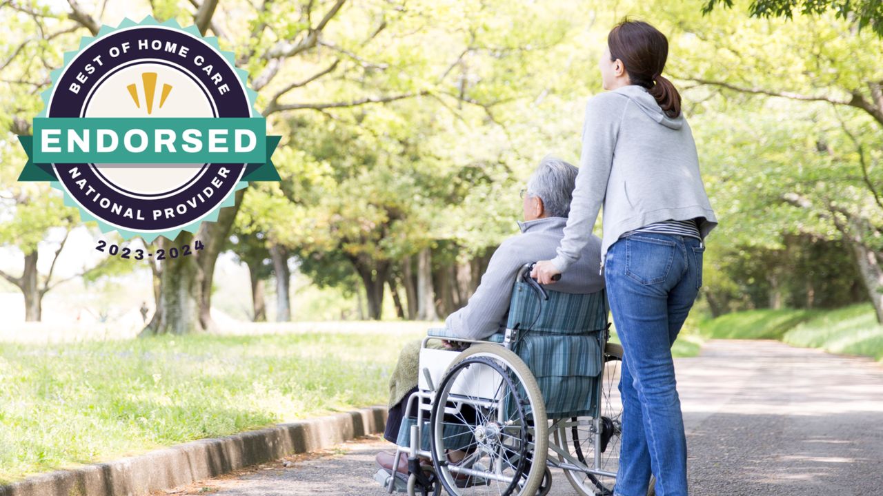 A caregiver provides home care as they push an elderly person in a wheelchair along a park path. A badge in the image reads "Best of Home Care Endorsed National Provider 2023-2024.