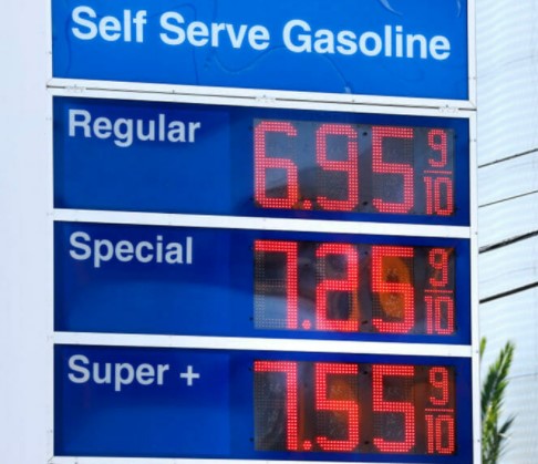 Gas station price sign showing Regular gas at $6.95 9/10, Special gas at $7.25 9/10, and Super+ gas at $7.55 9/10 near a company offering personal care services for seniors.