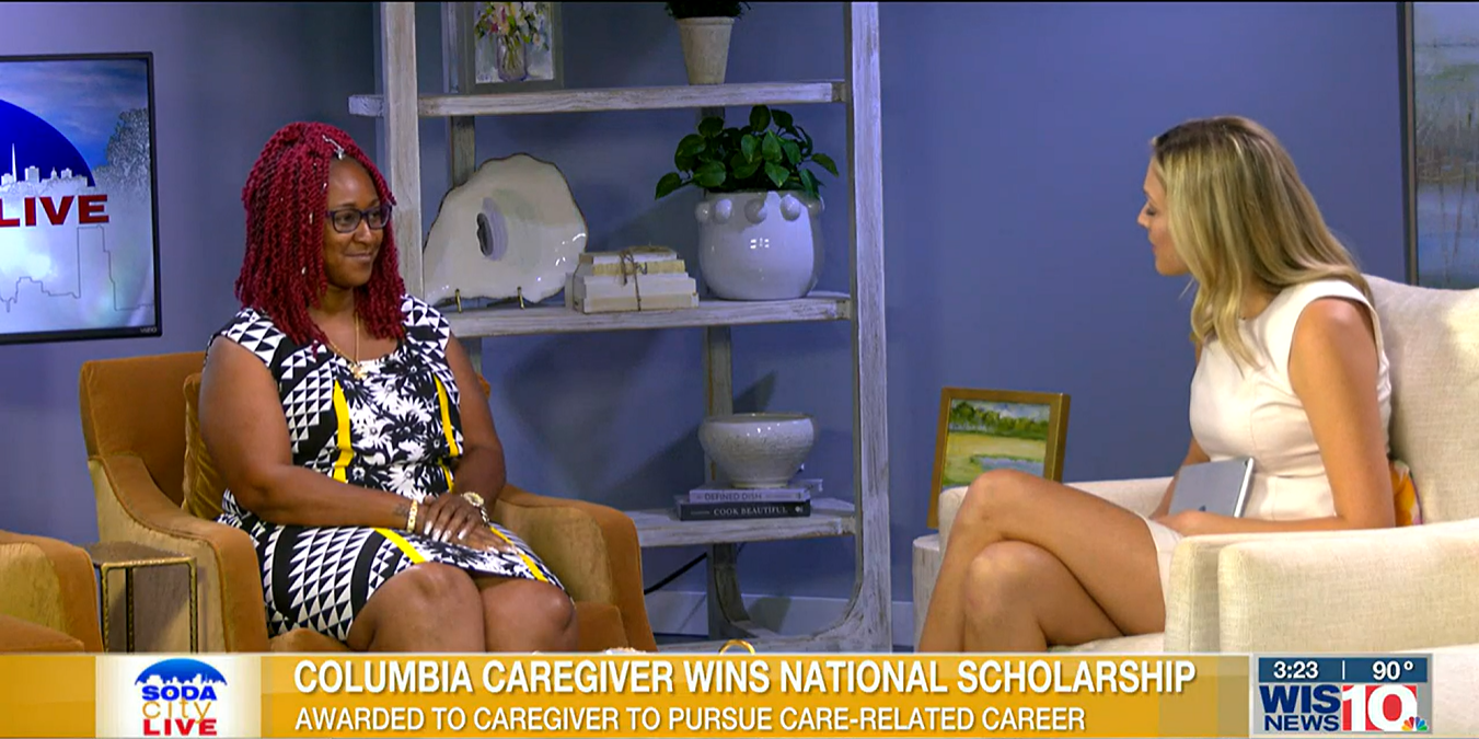 A woman is being interviewed on a talk show. The screen reads, "Columbia Caregiver Wins National Scholarship." The time and temperature are shown as 3:23 and 90°. She highlights the importance of personal care services in her journey to success.