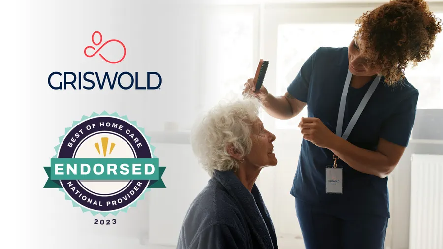 A caregiver delicately brushes an elderly woman's hair, embodying the essence of personal care services. The image features the Griswold Home Care logo and a badge reading "Best of Home Care Endorsed National Provider 2023." This scene exemplifies the perfect care pairing for your loved one.