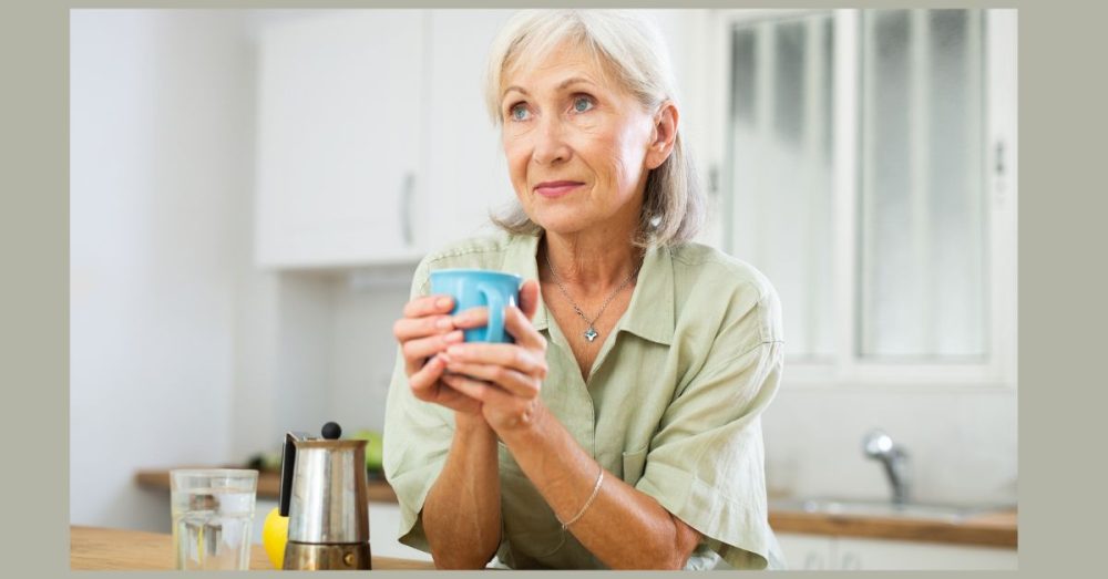 An elderly woman holds a blue mug